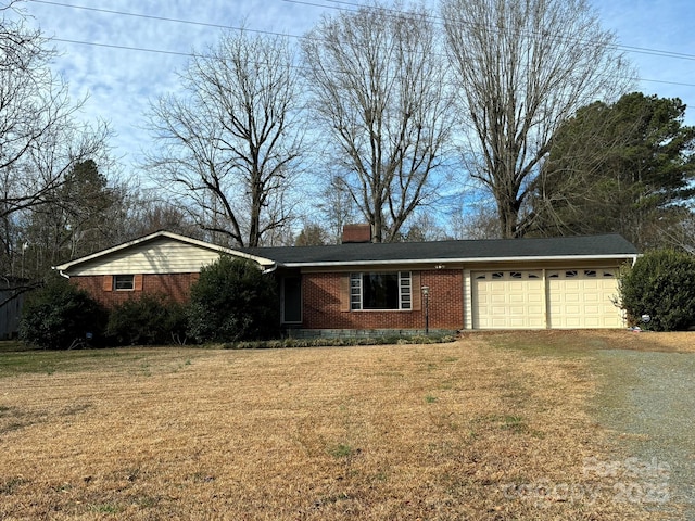 ranch-style house with driveway, brick siding, a front lawn, and a chimney