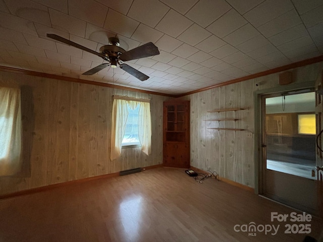 unfurnished room with baseboards, ceiling fan, wood finished floors, and crown molding