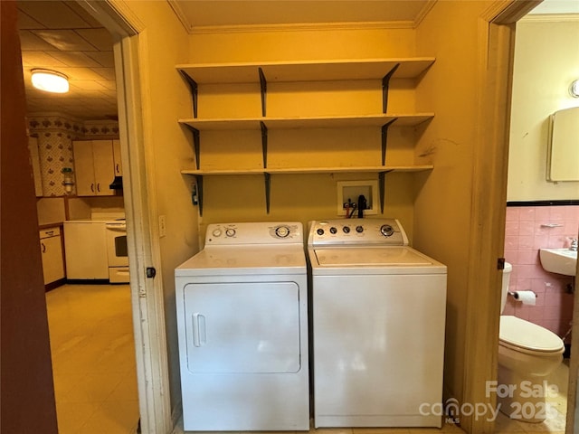 laundry area with laundry area, a wainscoted wall, washing machine and clothes dryer, crown molding, and tile walls