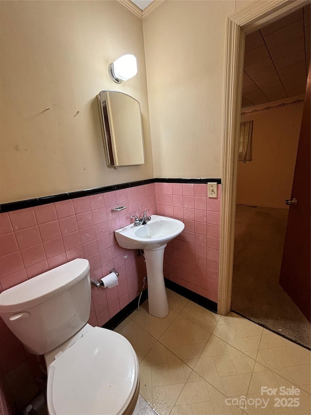 half bath with wainscoting, toilet, and tile walls