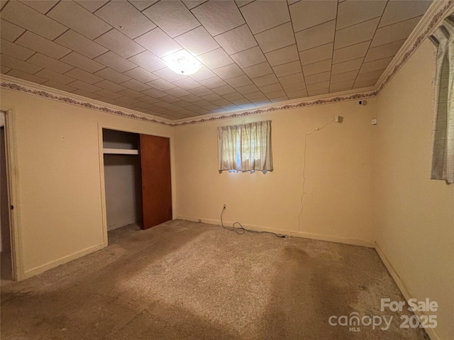 unfurnished bedroom featuring ornamental molding, a closet, light colored carpet, and baseboards