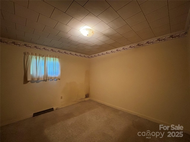 empty room featuring carpet flooring, visible vents, and baseboards