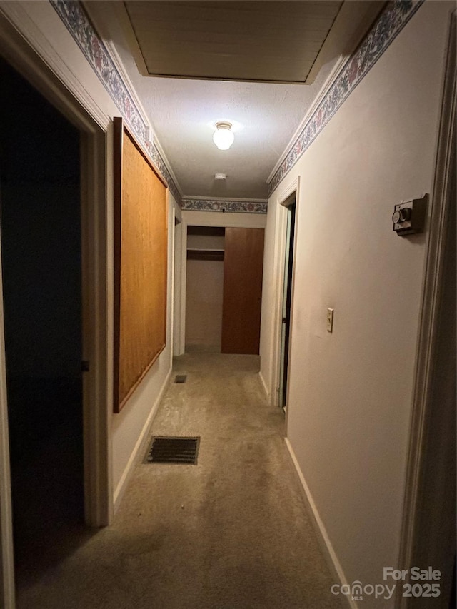 hallway with carpet flooring, visible vents, and baseboards