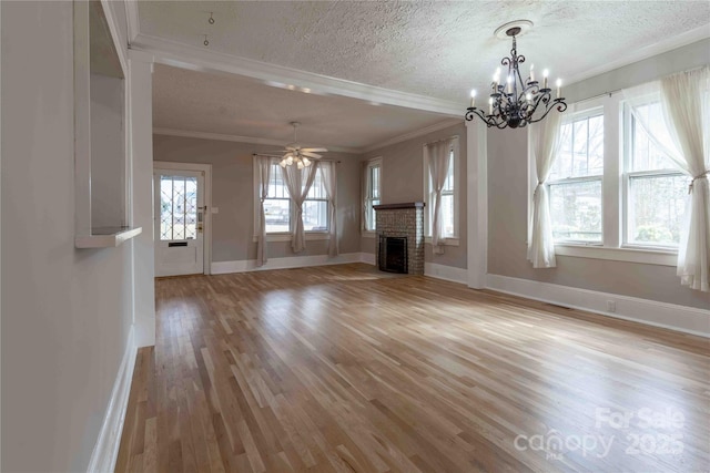 unfurnished living room featuring ceiling fan with notable chandelier, a fireplace, crown molding, a textured ceiling, and light wood-type flooring