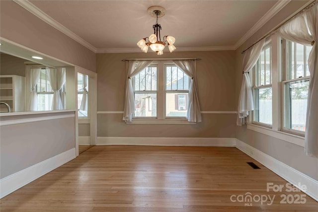 unfurnished dining area featuring crown molding, light hardwood / wood-style flooring, and a chandelier