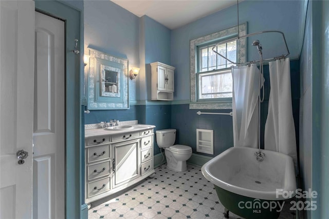 bathroom featuring vanity, toilet, and tile walls