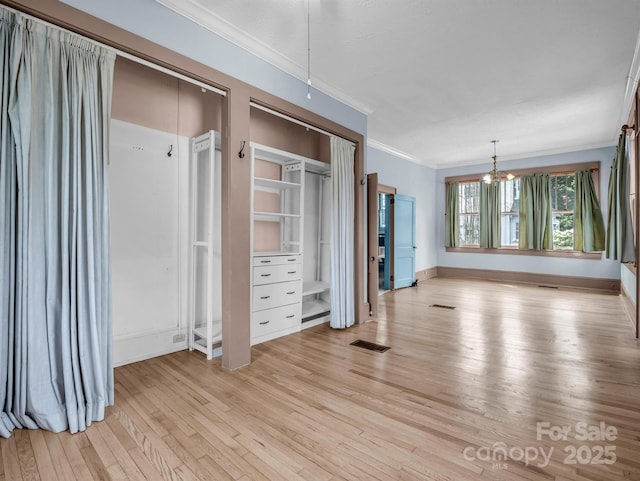 unfurnished bedroom featuring multiple closets, crown molding, a chandelier, and light wood-type flooring