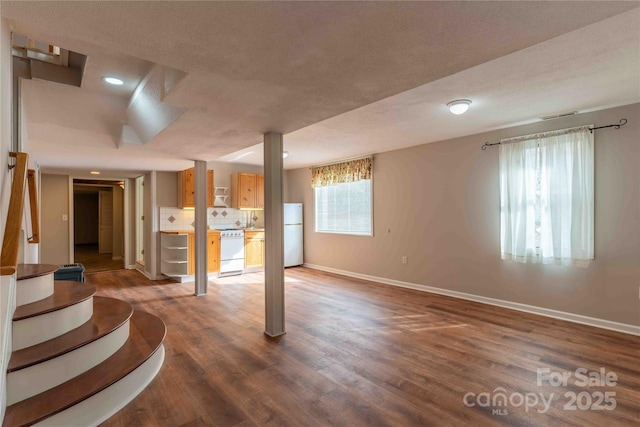 basement featuring white refrigerator, wood-type flooring, and a textured ceiling