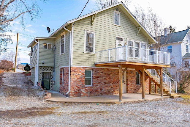 rear view of house with a wooden deck and a patio area