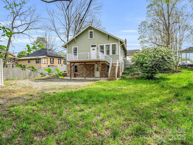 rear view of house with a wooden deck, a yard, and a patio