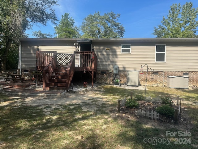 back of property featuring a lawn and a deck