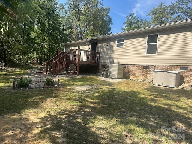 rear view of property featuring central AC unit, a lawn, and a wooden deck