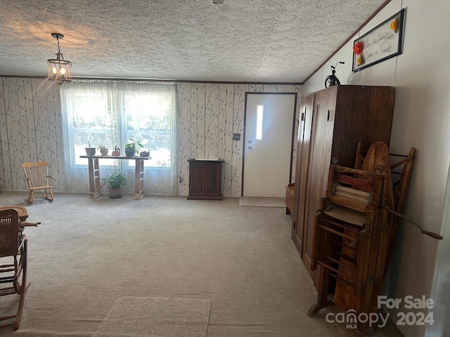 misc room with a notable chandelier, a textured ceiling, and carpet floors