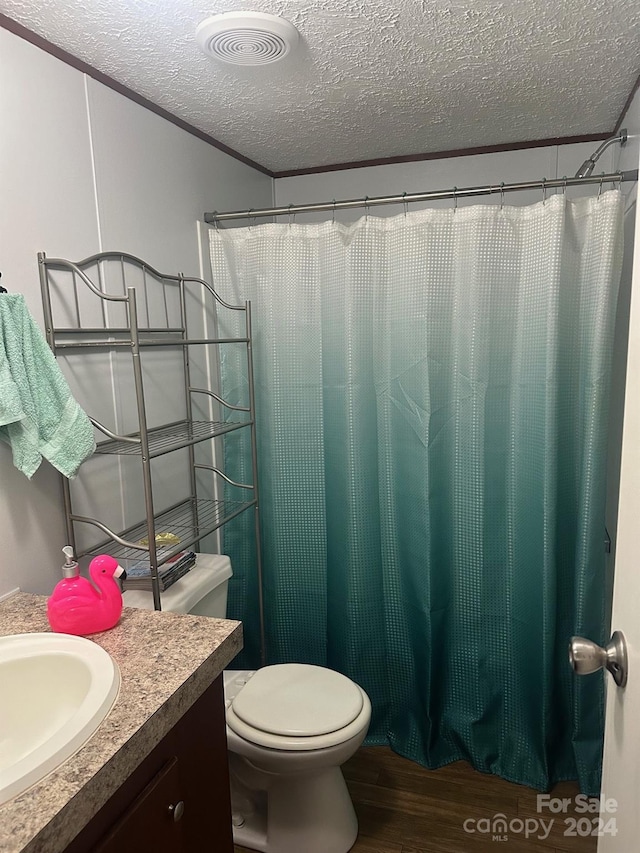 bathroom featuring toilet, hardwood / wood-style floors, crown molding, vanity, and a textured ceiling