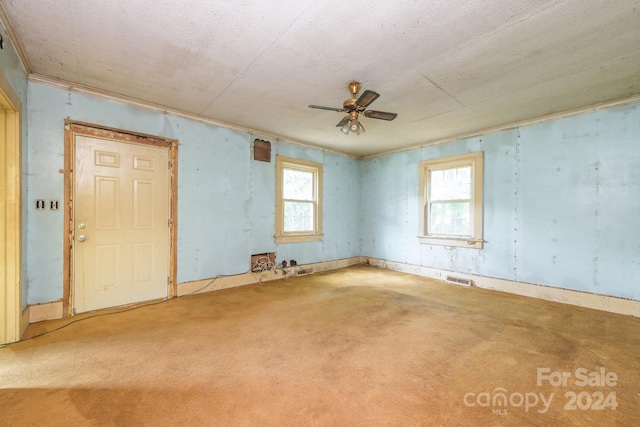 spare room featuring ceiling fan, light colored carpet, and a healthy amount of sunlight