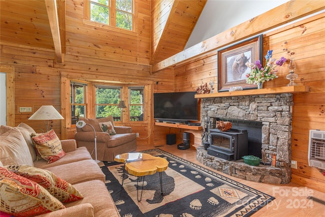 living room featuring beamed ceiling, wood-type flooring, a wood stove, heating unit, and wood walls