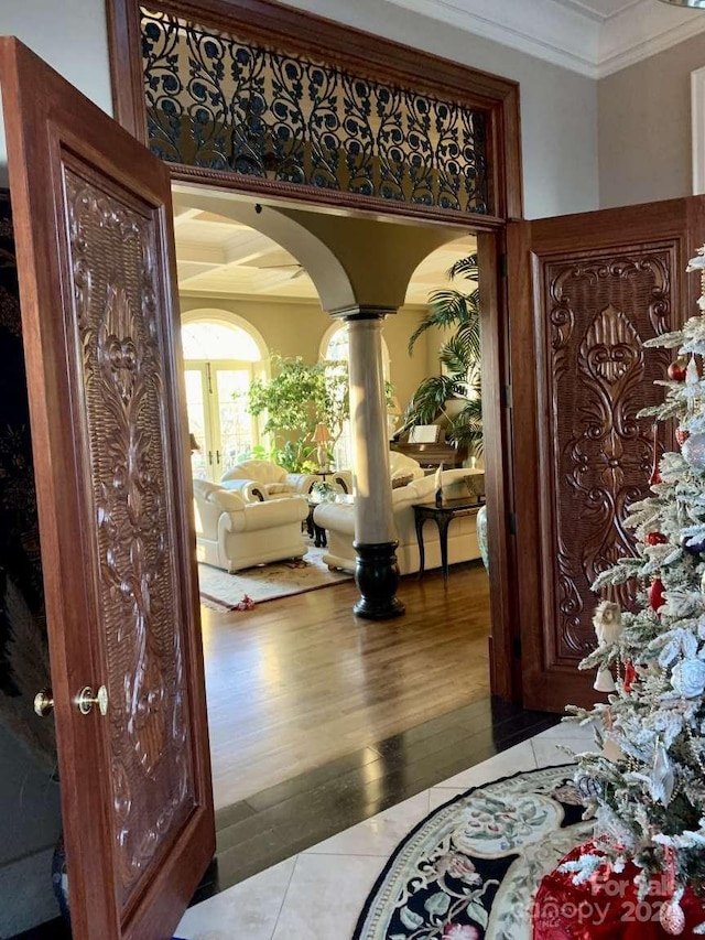 interior space featuring crown molding, wood-type flooring, and decorative columns