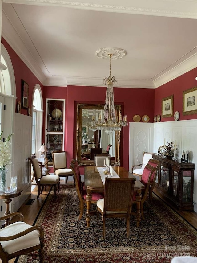 dining area with crown molding, a chandelier, and hardwood / wood-style flooring