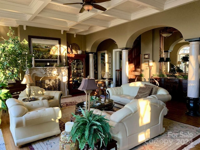 living room featuring coffered ceiling, beamed ceiling, a high end fireplace, wood-type flooring, and ceiling fan