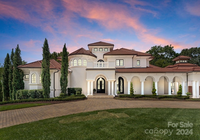 mediterranean / spanish house with french doors, a tile roof, a balcony, and stucco siding