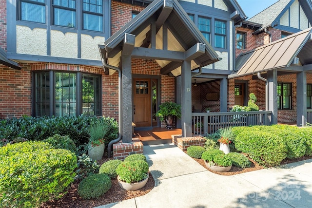 doorway to property with a porch and brick siding