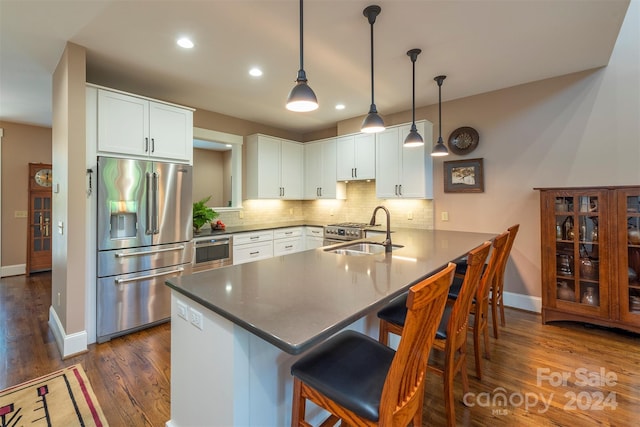kitchen featuring a peninsula, a sink, decorative backsplash, stainless steel refrigerator with ice dispenser, and a kitchen bar