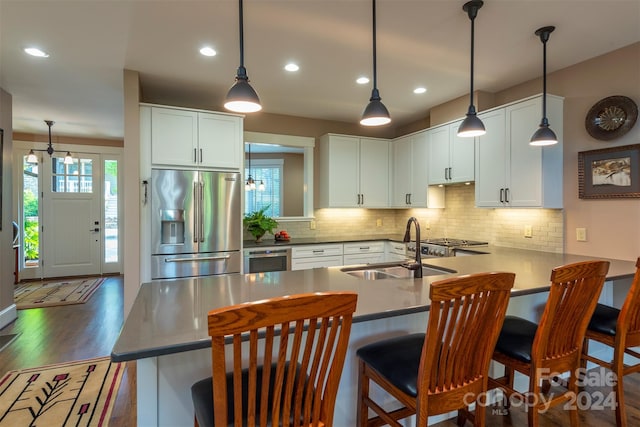 kitchen featuring a sink, dark wood finished floors, a peninsula, white cabinets, and high end refrigerator