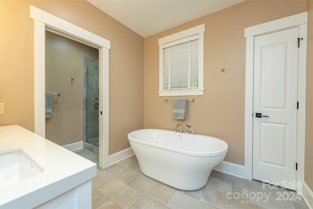 bathroom featuring vanity, a shower stall, a freestanding tub, and baseboards