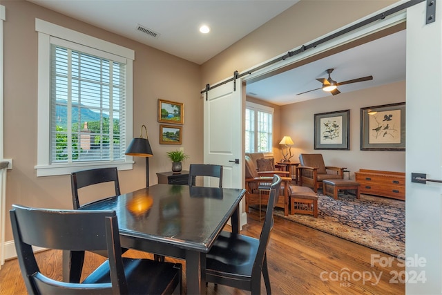 dining space with visible vents, ceiling fan, a barn door, recessed lighting, and wood finished floors
