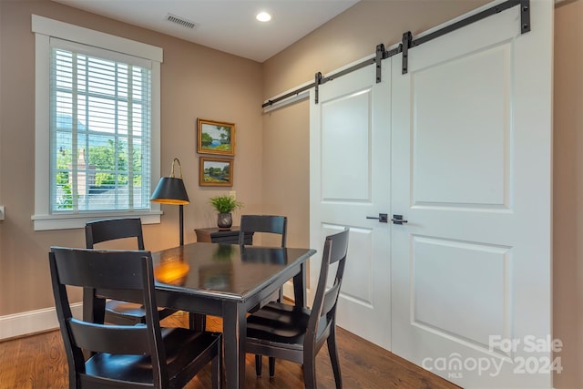 dining space with a barn door, recessed lighting, visible vents, and dark wood-type flooring