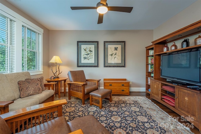 living area featuring wood finished floors, a ceiling fan, and baseboards