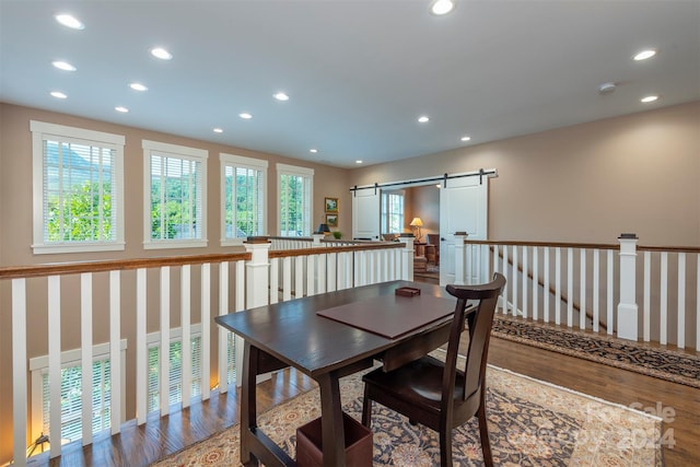 dining area with a barn door, recessed lighting, and wood finished floors