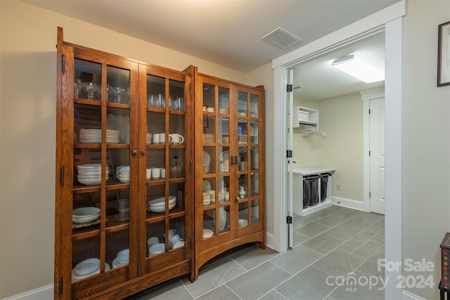 hallway featuring tile patterned floors, visible vents, and baseboards