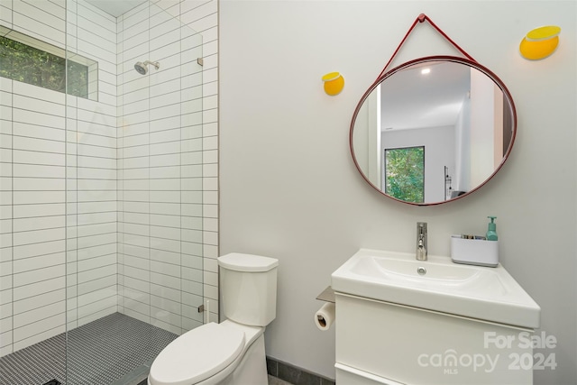 bathroom with tiled shower, vanity, and toilet