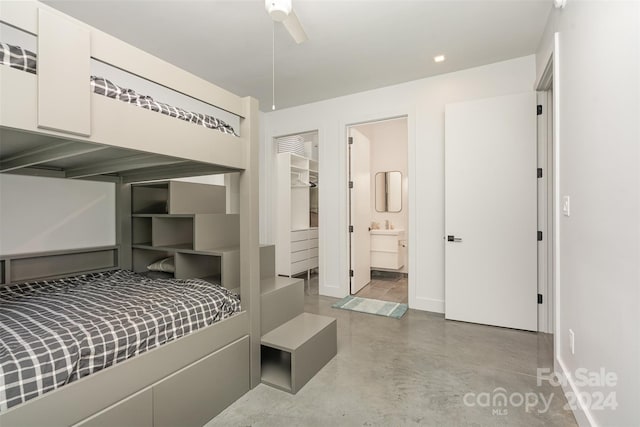 bedroom with ceiling fan, ensuite bathroom, and concrete floors