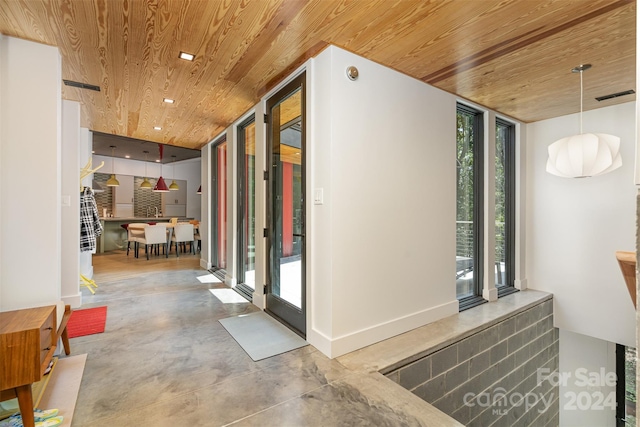 corridor featuring a wall of windows, wood ceiling, plenty of natural light, and concrete floors