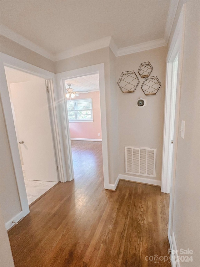 corridor with hardwood / wood-style floors and ornamental molding