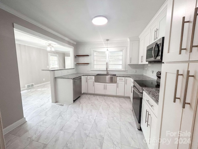 kitchen with sink, appliances with stainless steel finishes, kitchen peninsula, pendant lighting, and white cabinets