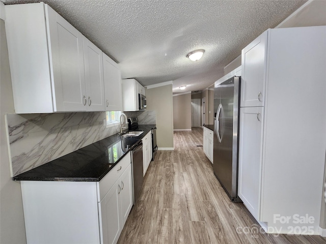 kitchen with sink, backsplash, stainless steel appliances, white cabinets, and light wood-type flooring