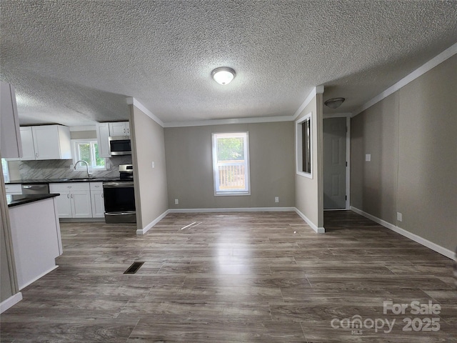 unfurnished living room featuring dark hardwood / wood-style flooring, sink, and crown molding