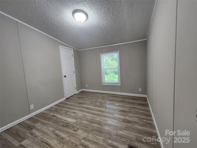 spare room featuring crown molding, hardwood / wood-style flooring, and a textured ceiling