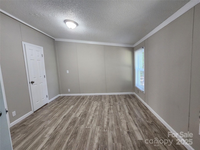 empty room with ornamental molding, hardwood / wood-style floors, and a textured ceiling