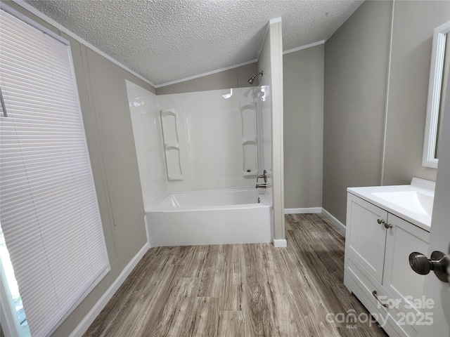 bathroom with bathing tub / shower combination, a textured ceiling, ornamental molding, vanity, and hardwood / wood-style flooring