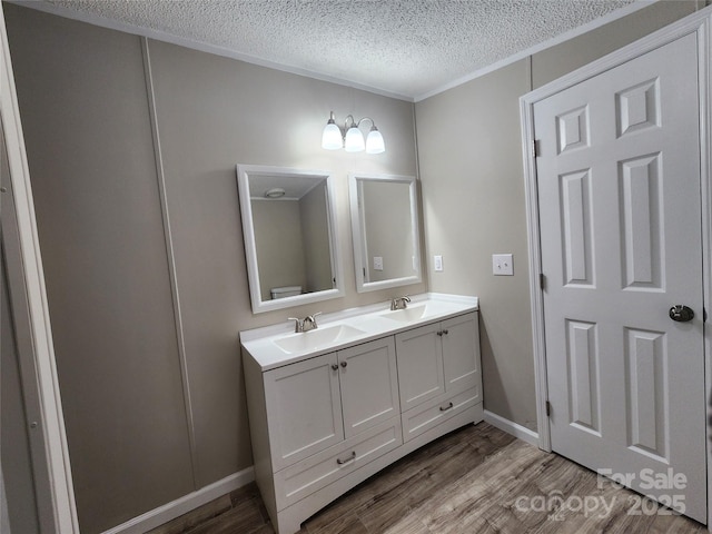 bathroom with hardwood / wood-style flooring, ornamental molding, vanity, and a textured ceiling