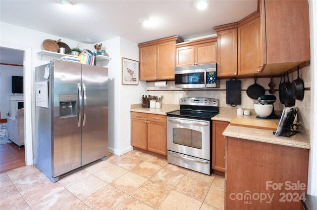 kitchen featuring appliances with stainless steel finishes, tasteful backsplash, and light tile patterned flooring