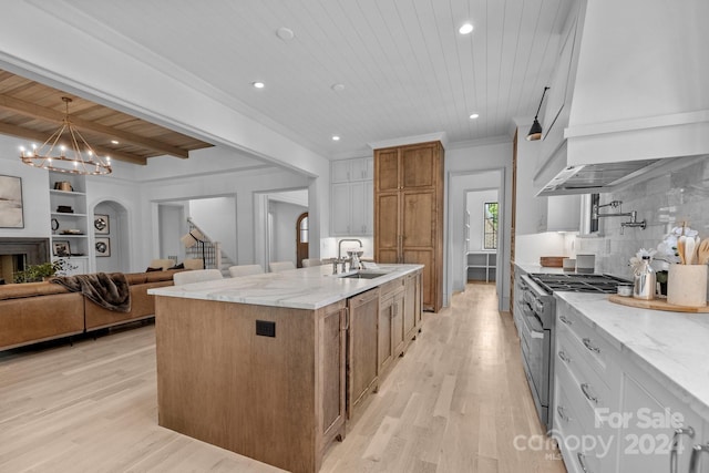 kitchen with backsplash, stainless steel stove, light hardwood / wood-style flooring, wooden ceiling, and a center island with sink