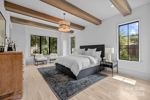 bedroom with beam ceiling, light hardwood / wood-style flooring, and multiple windows