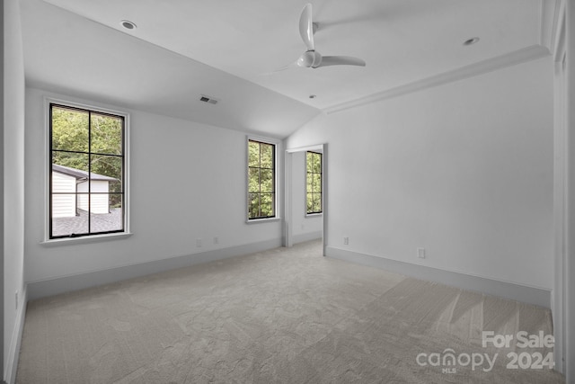 empty room featuring plenty of natural light, lofted ceiling, and light carpet