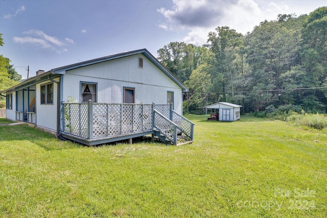 rear view of house with a deck, a storage shed, and a lawn