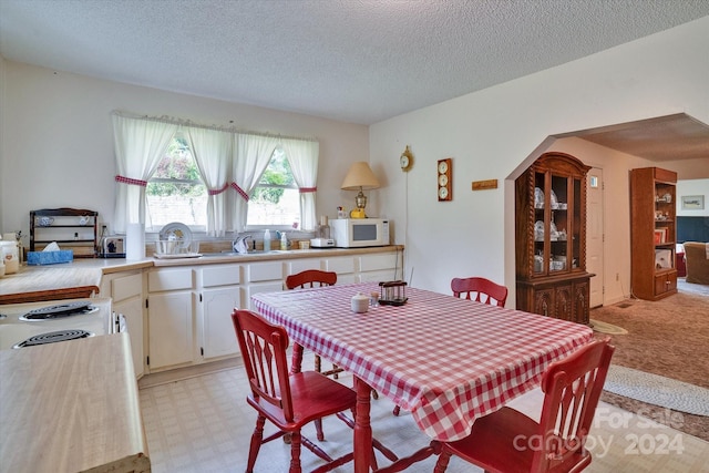 dining area featuring a textured ceiling and light carpet